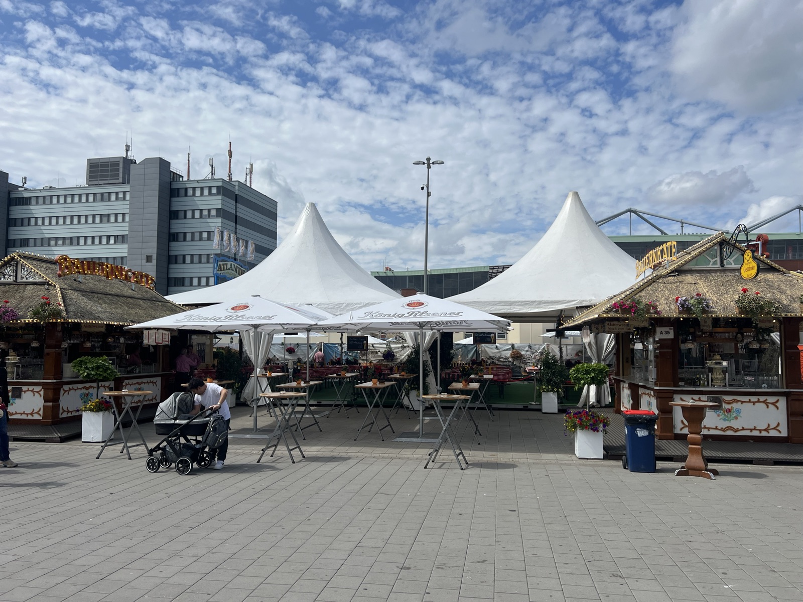 Weiße Zeltdächer und Stehtische im Außenbereich, im Hintergrund Hochhäuser