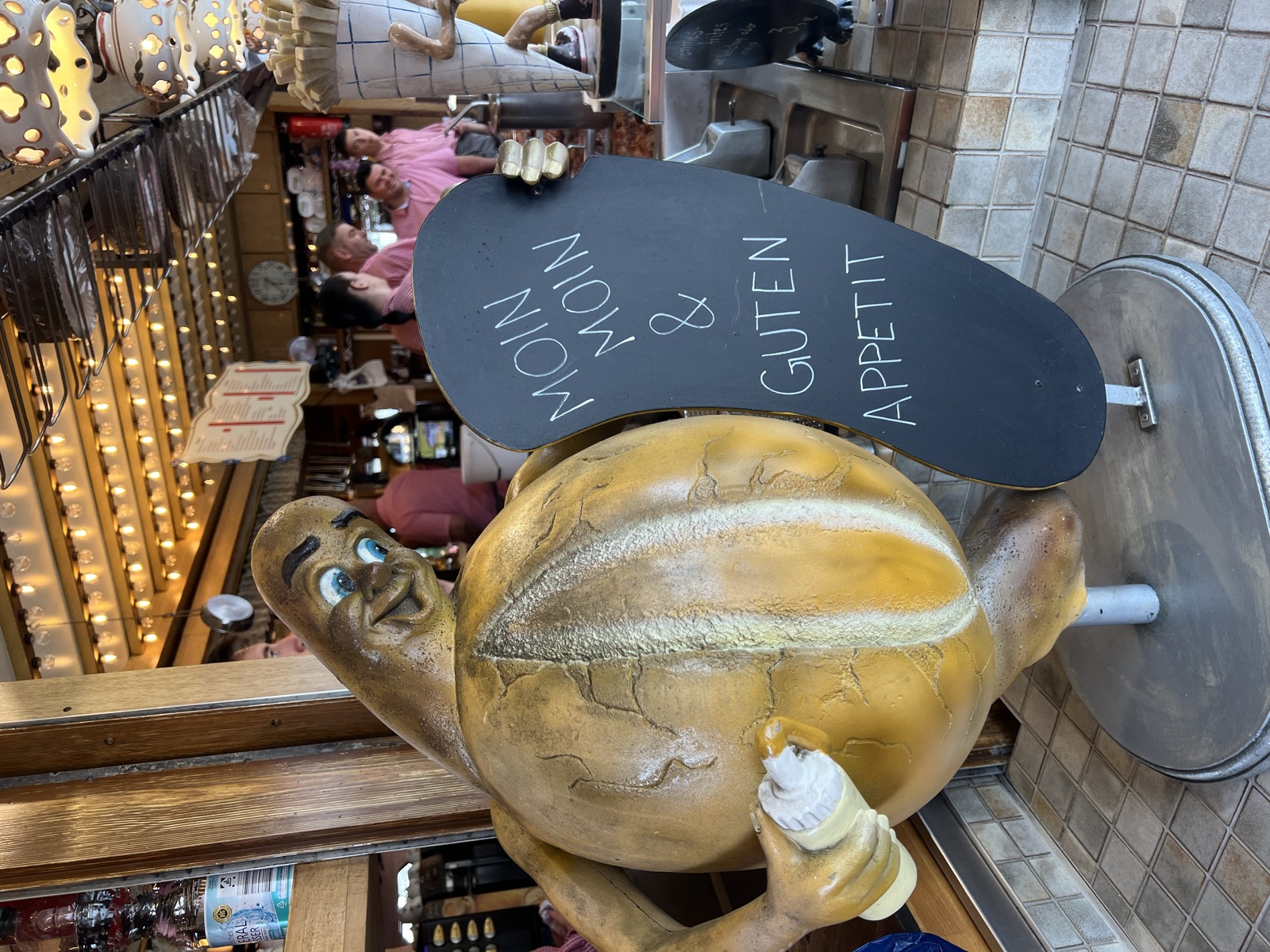Lustige Maskottchen-Figur mit Tafel „Moin Moin & Guten Appetit“ am Eingang