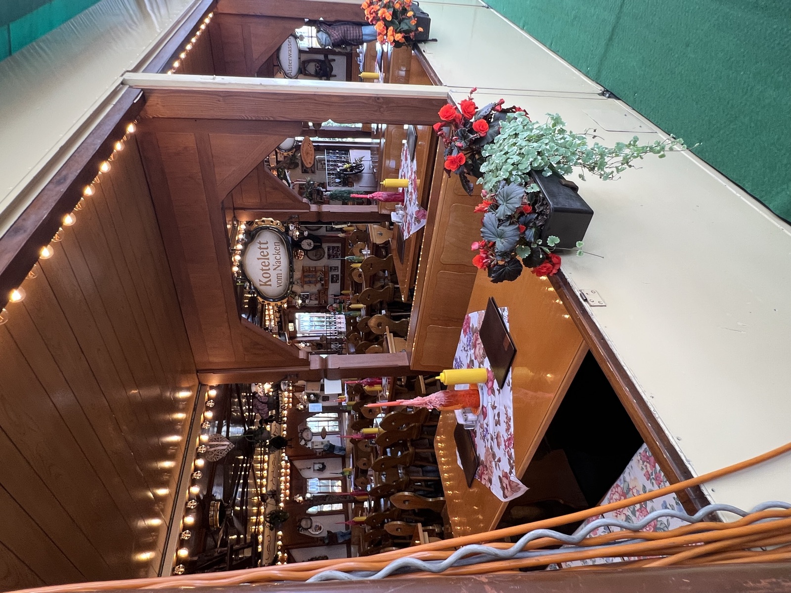 Holzvertäfelte Gaststube mit eingedeckten Tischen und Blumenschmuck